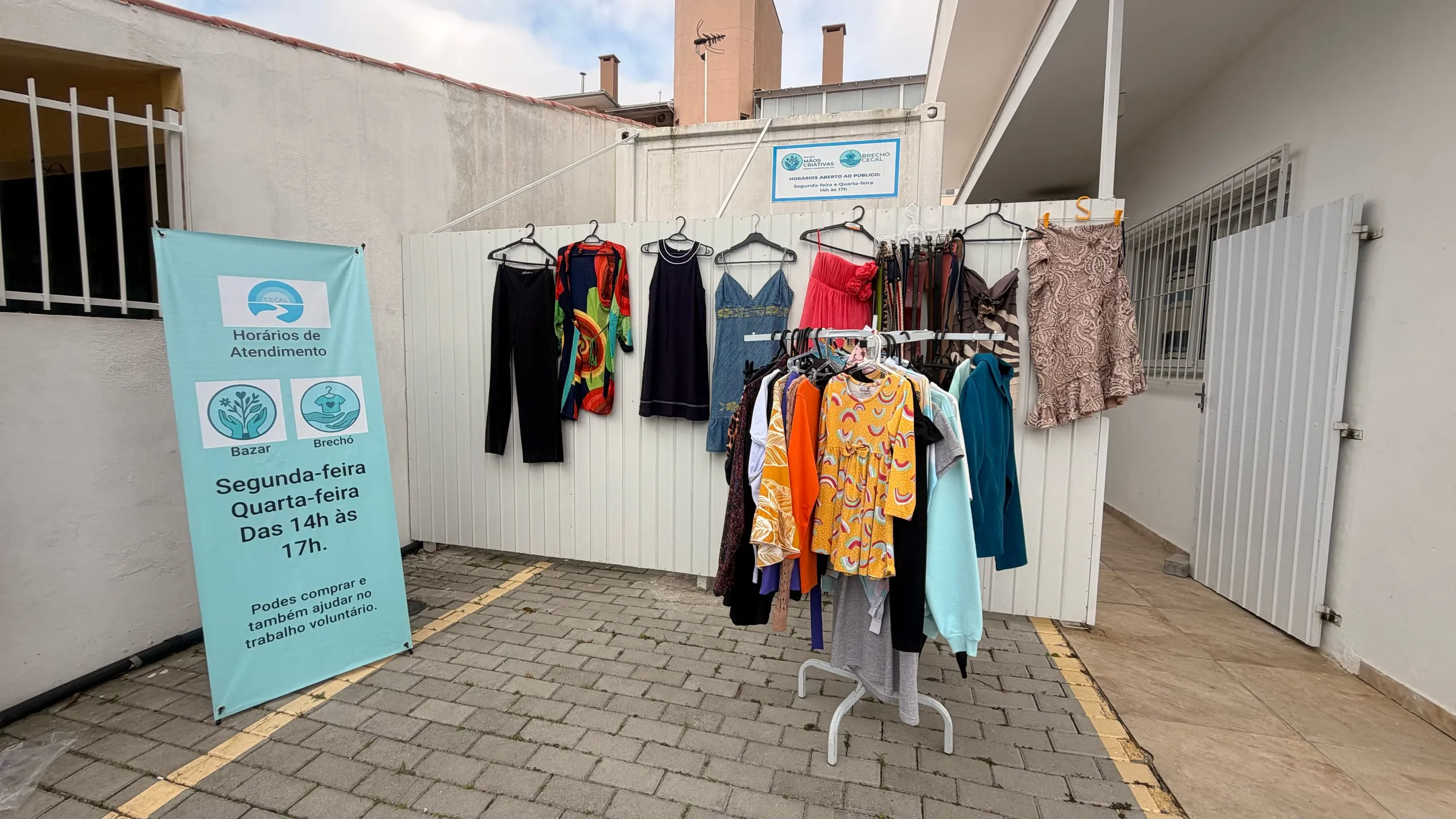 O banner na entrada da casa com os horários do bazar e do brechó: segunda e quarta, das 14h às 17h.