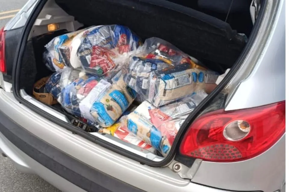 O porta-malas de um carro cheio de cestas básicas, pronto para a entrega.