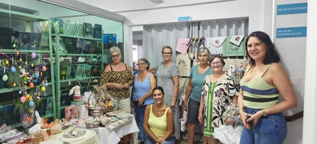O grupo Mãos Criativas reunido diante de uma vitrine com peças de artesanato.