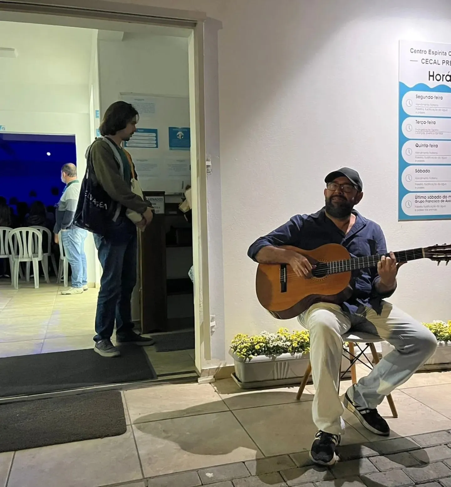 Um voluntário toca violão na entrada da casa.